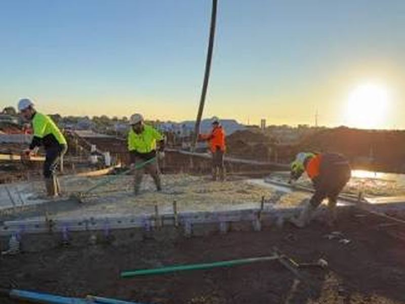 Concreting crew pouring a slab at sunrise